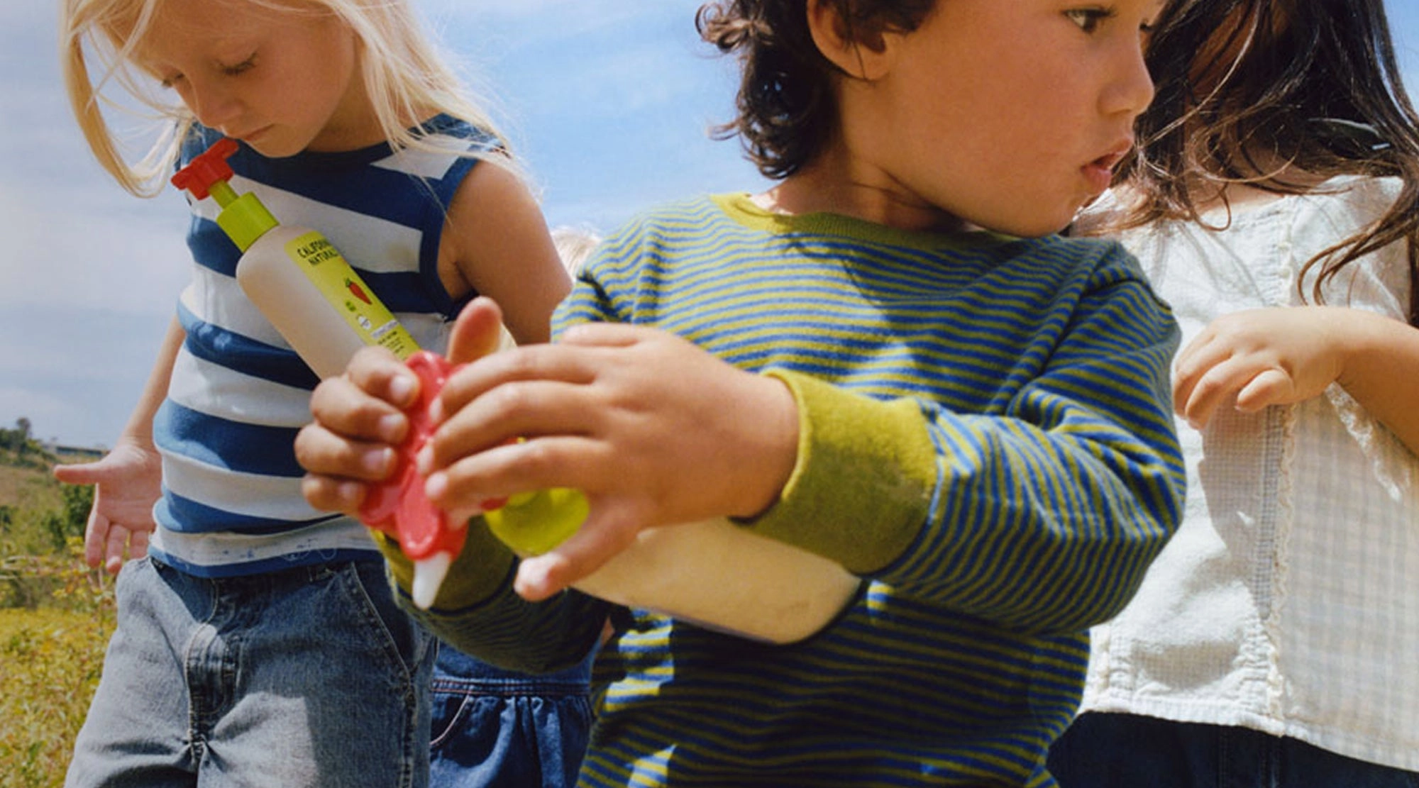 Kids at bathtime in the sun, holding California Naturals pump bottles